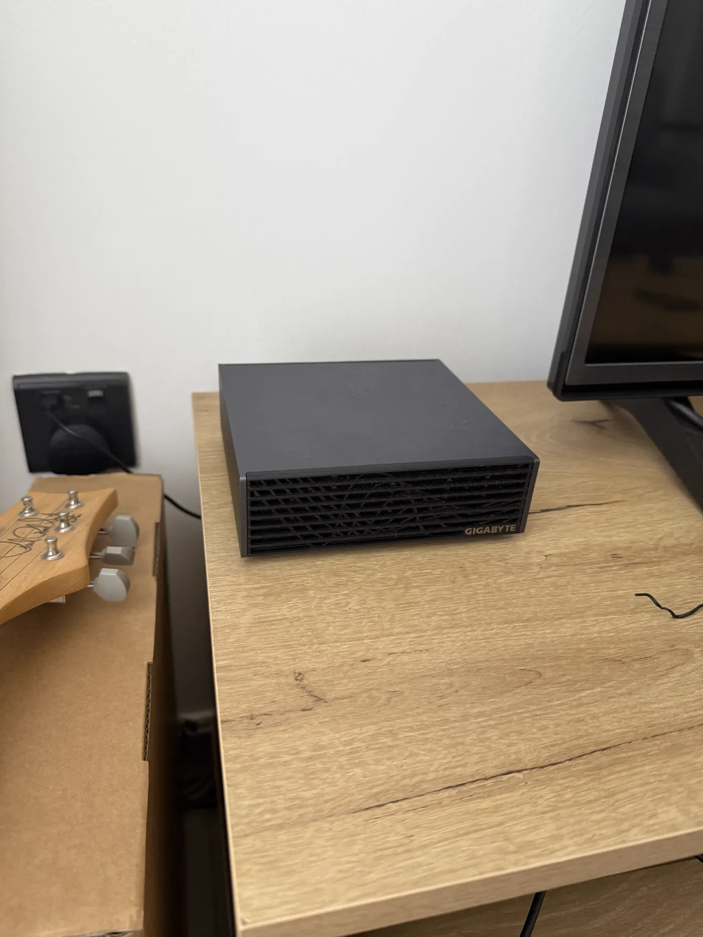 The Gigabyte AI TOP ATOM on my desk, next to the monitor, with my guitar’s headstock peeking in from the left