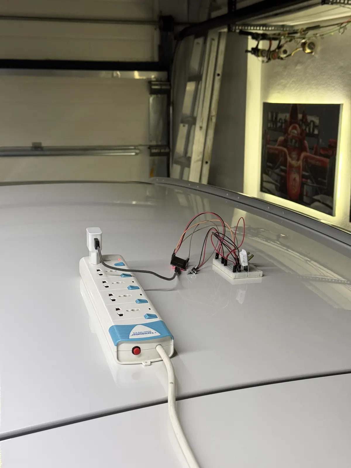 The prototype: an ESP32 on a breadboard with an IR LED and a DHT22 sensor, powered from a USB charger on a power strip